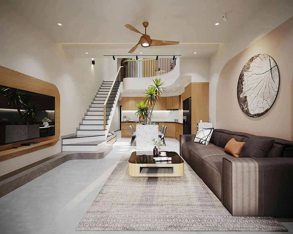 Mẫu thiết kế phòng khách liền bếp nhà ống với sofa xám, cầu thang và khu vực bếp ở phía sau.