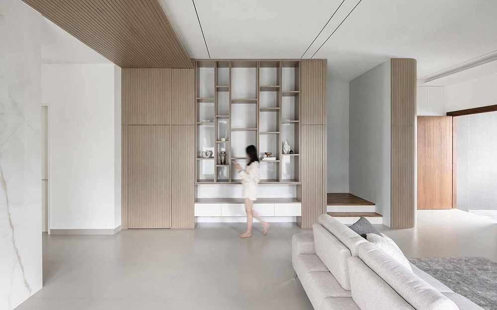 Hệ tủ kệ trang trí kịch trần ngăn cách không gian phòng khách và lối đi trong thiết kế nội thất Nhà Bè.