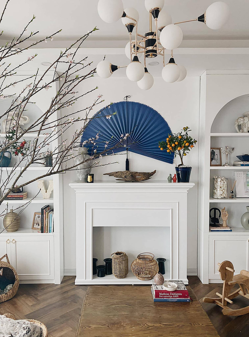 Trang trí phòng khách ngày tết khu vực lò sưởi với quạt giấy xanh và đào phai